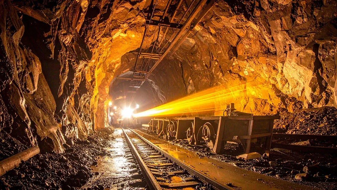 Túnel de mina con vagonetas y rieles iluminados