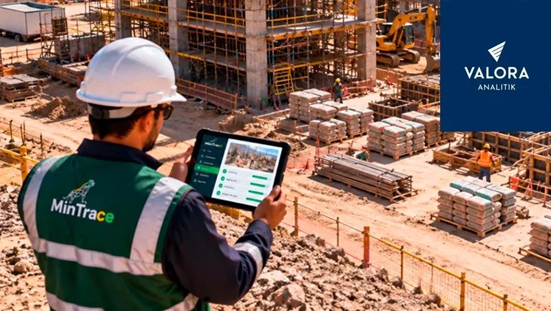 Profesional con chaleco de MinTrace revisa en una tableta el reporte de trazabilidad en una obra con materiales de construcción